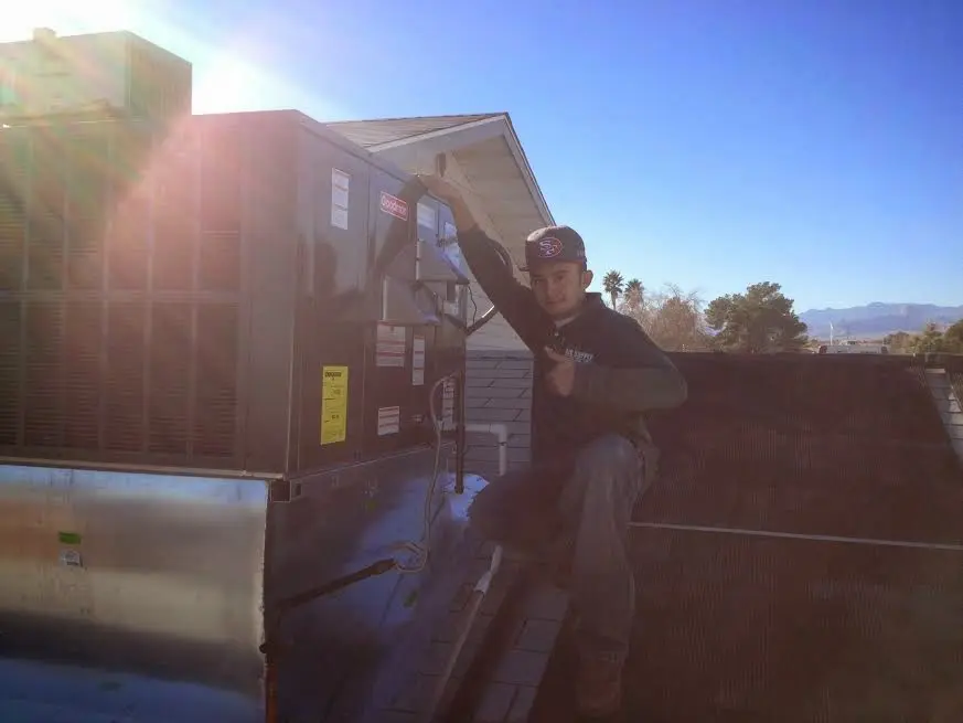 HVAC technician performing Air Duct Cleaning on a rooftop unit in Sunbury